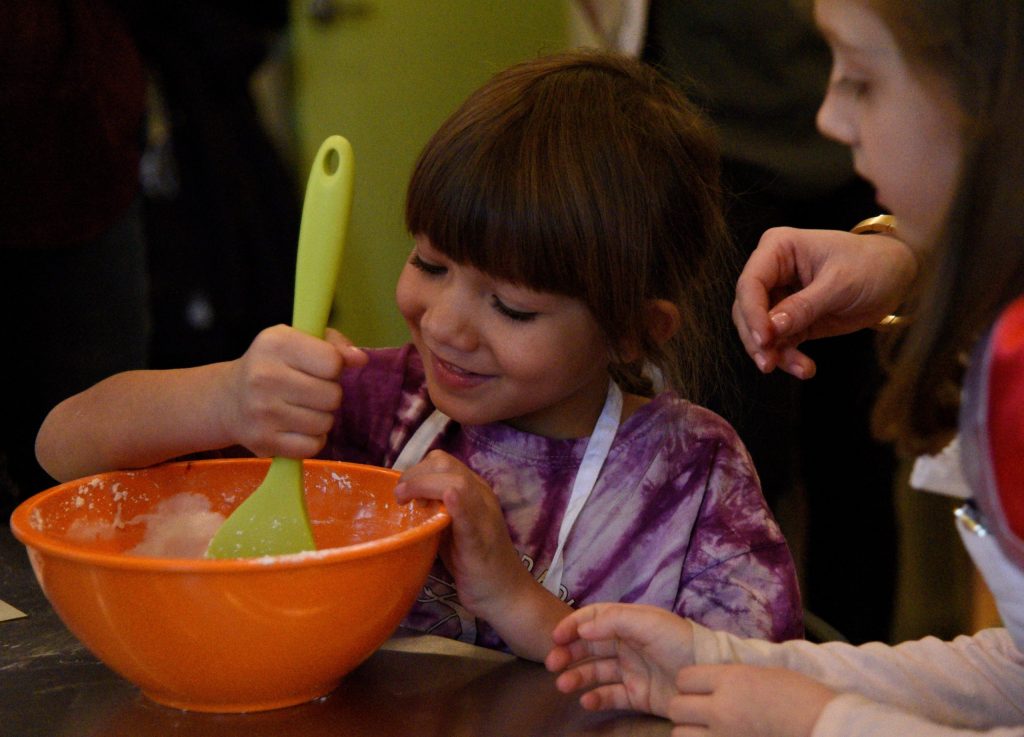 a little boy that is holding a bowl of food