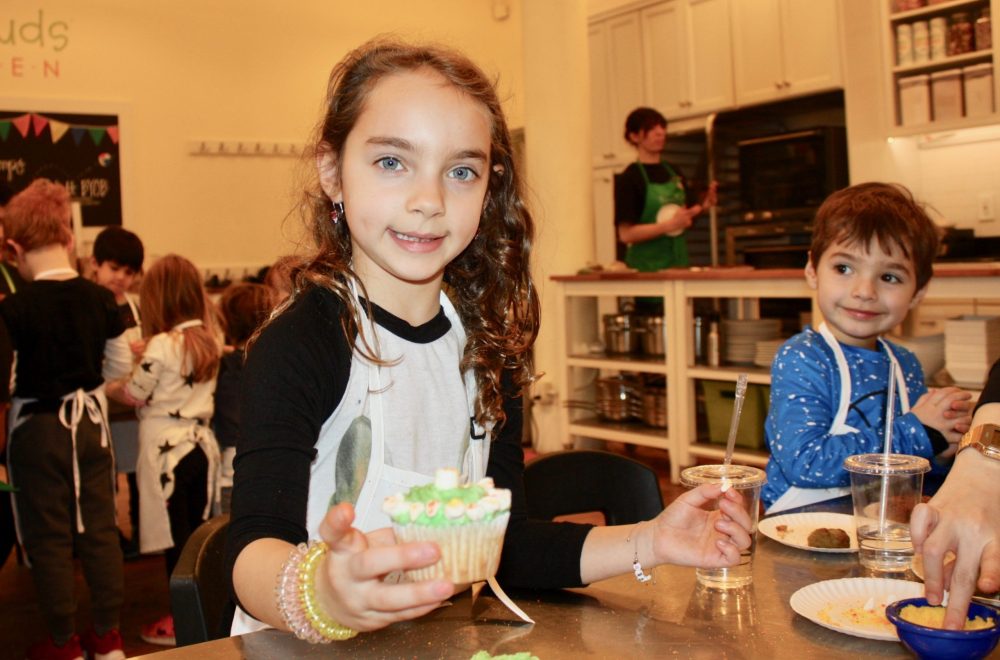 girl smiling holding a decorated cupcake