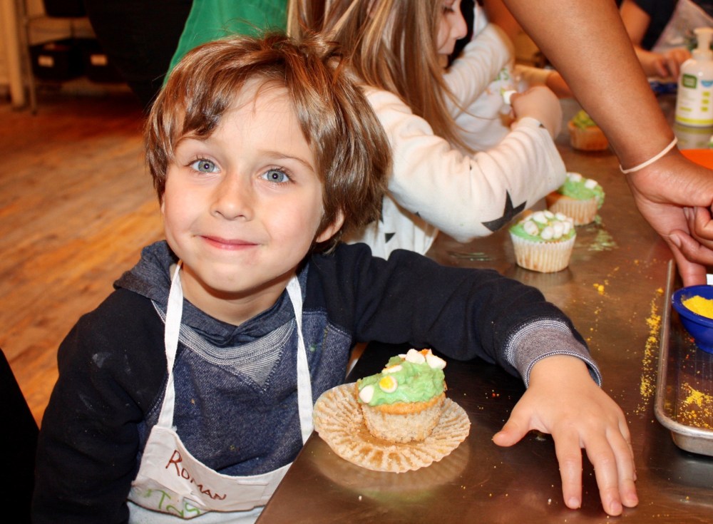 little boy with a bite out of his decorated cupcake