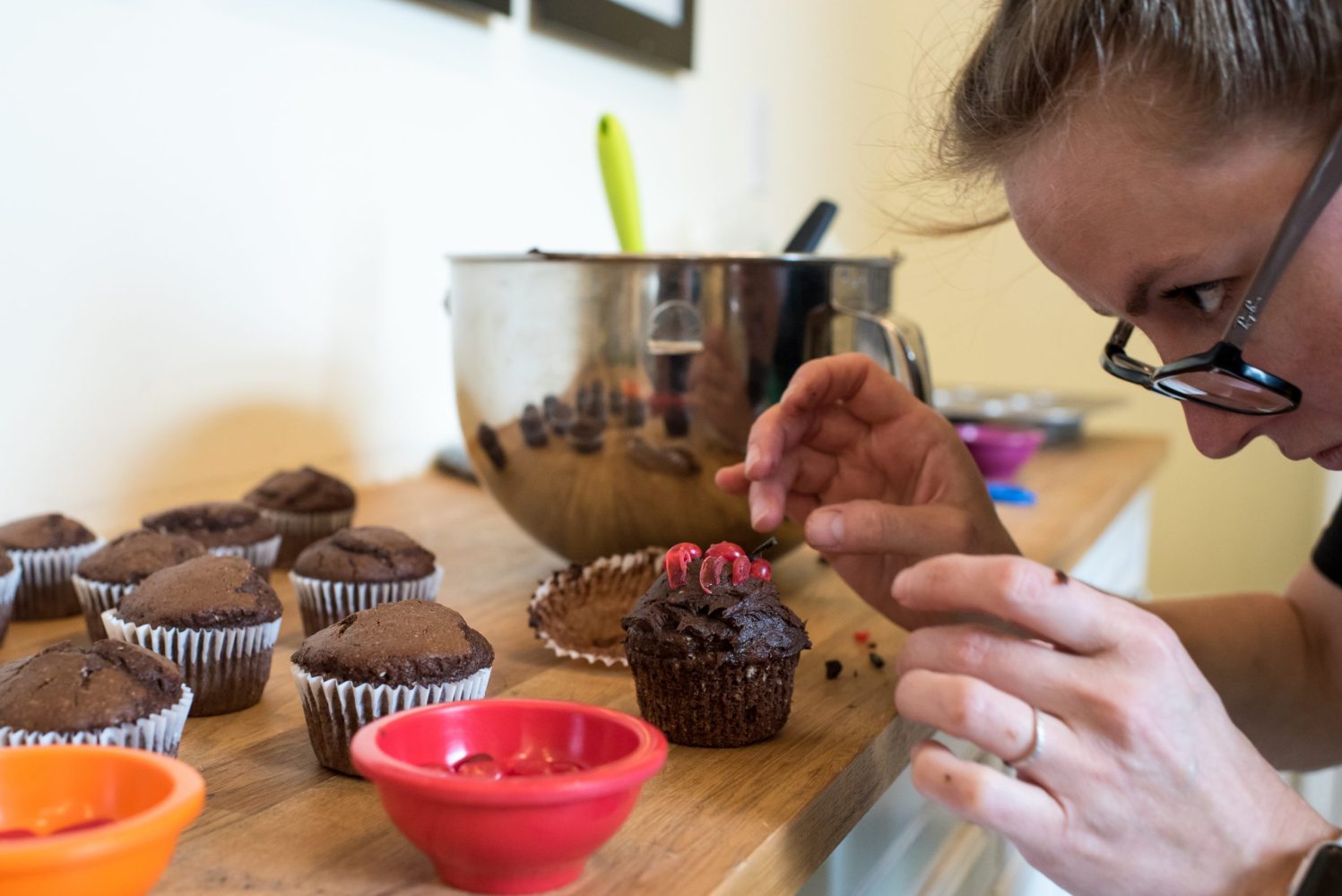person frosting and decorating a chocolate cupcake