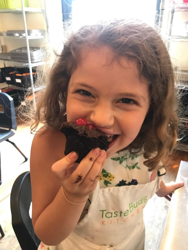 little girl eating a chocolate frosted cupcake