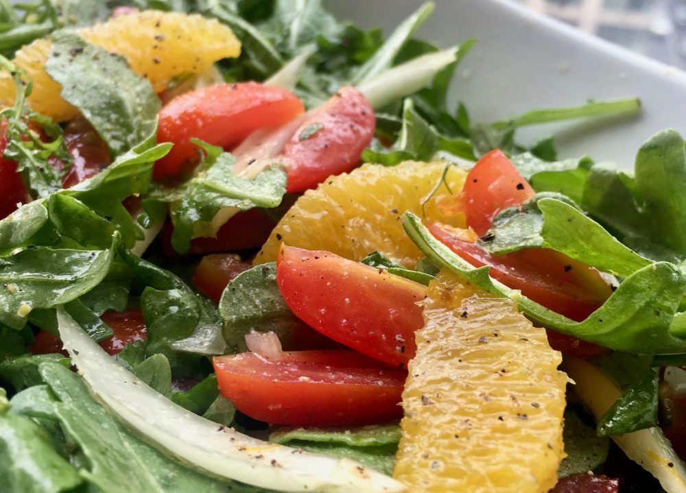 citrus fruit and tomatoes on arugula salad
