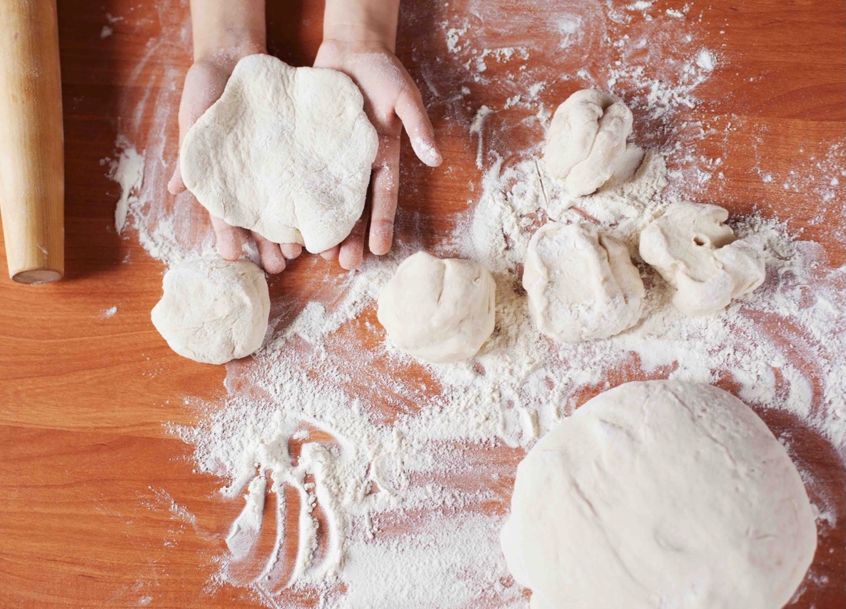 Child holding kneading dough balls of dough