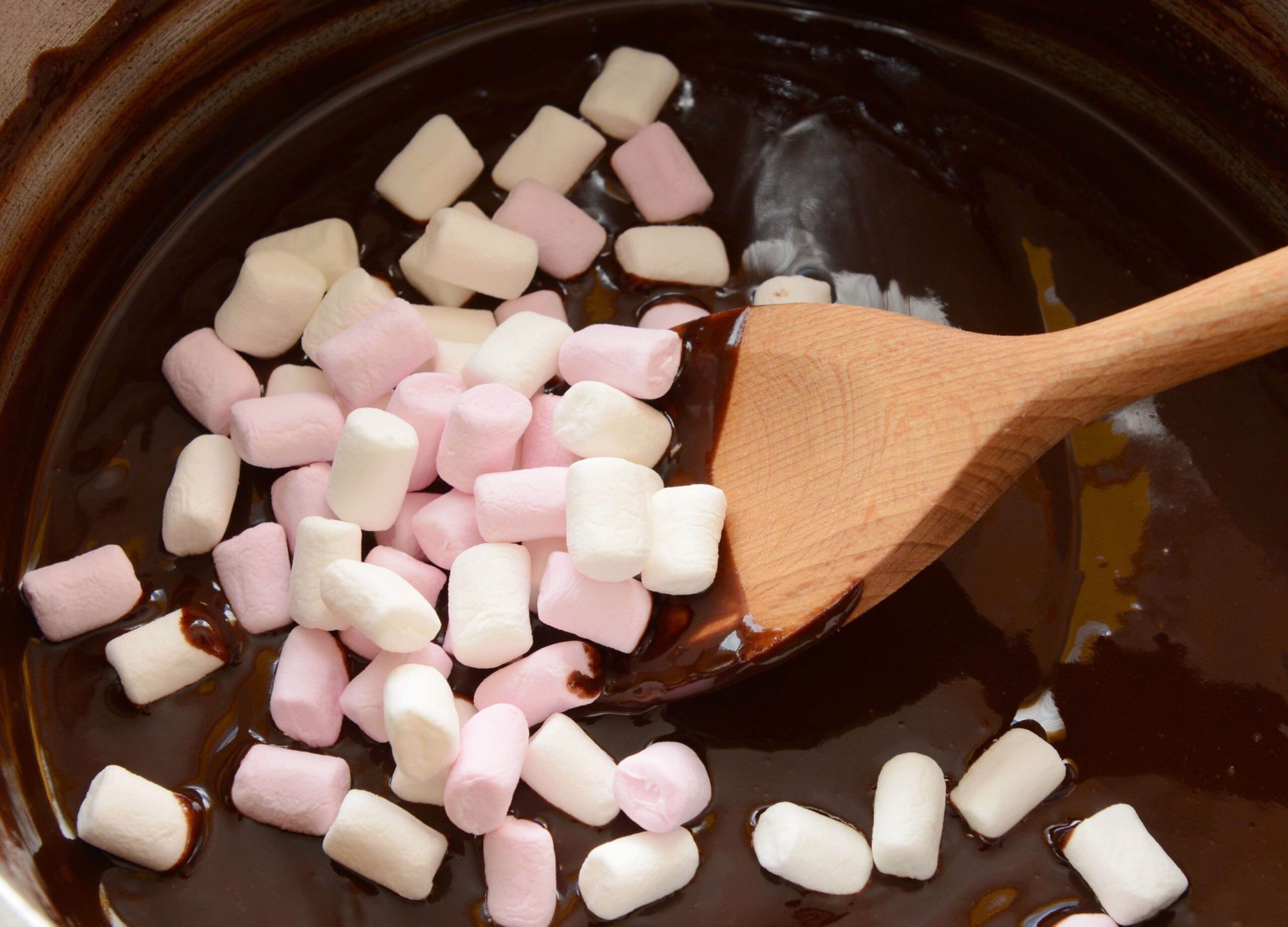 Chocolate-Lovers-Camp marshmallows in melted chocolate and a wooden spoon