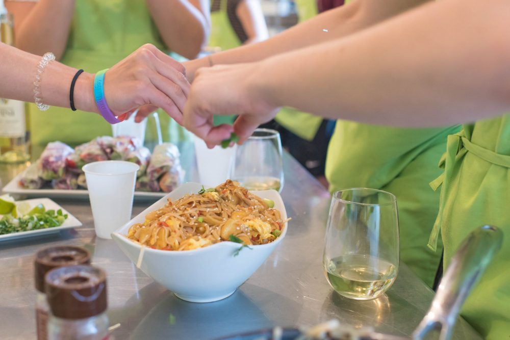 adults squeezing lime wedges onto their pad thai