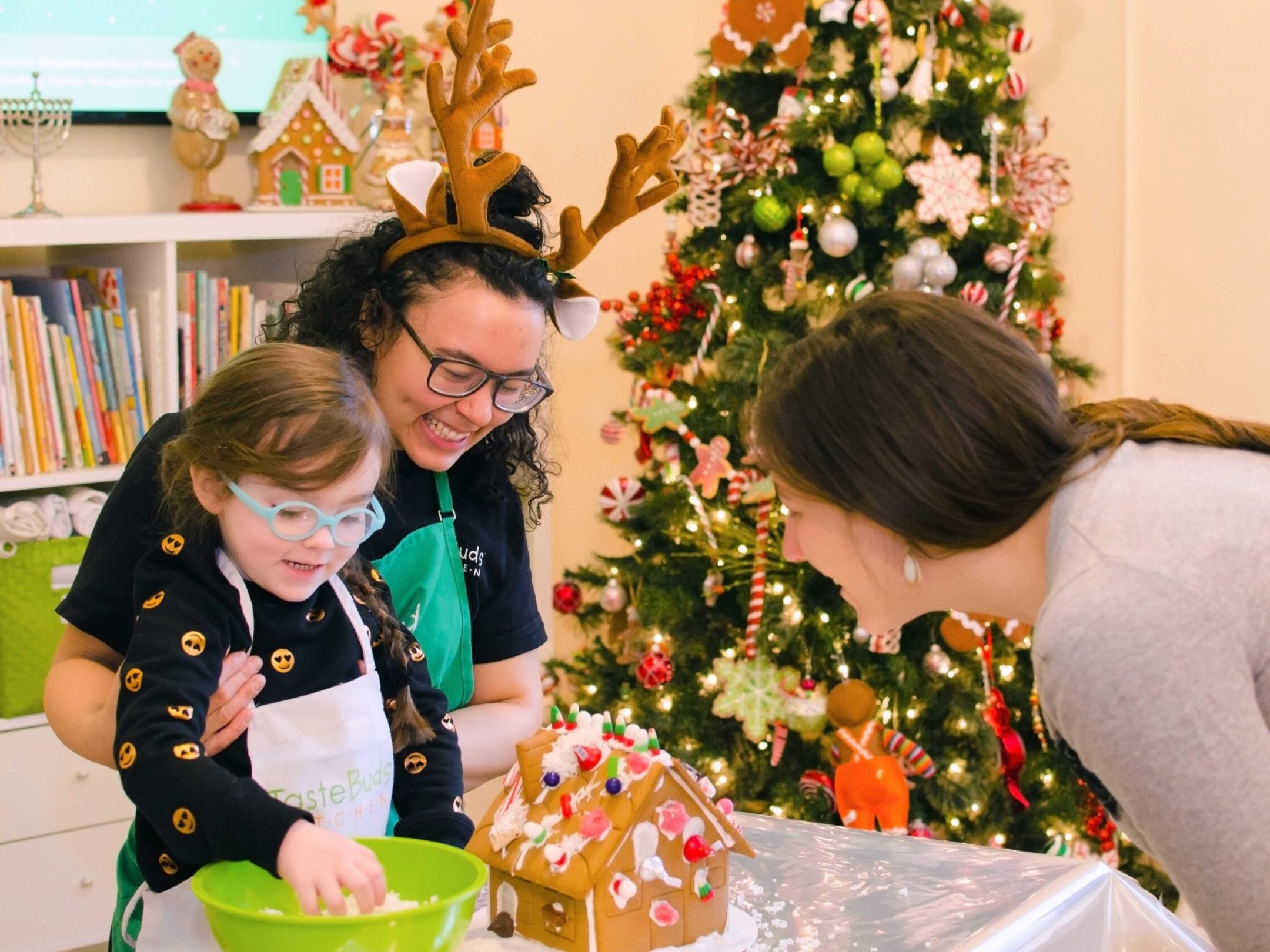 a mother and daughter decorating a gingerbread house