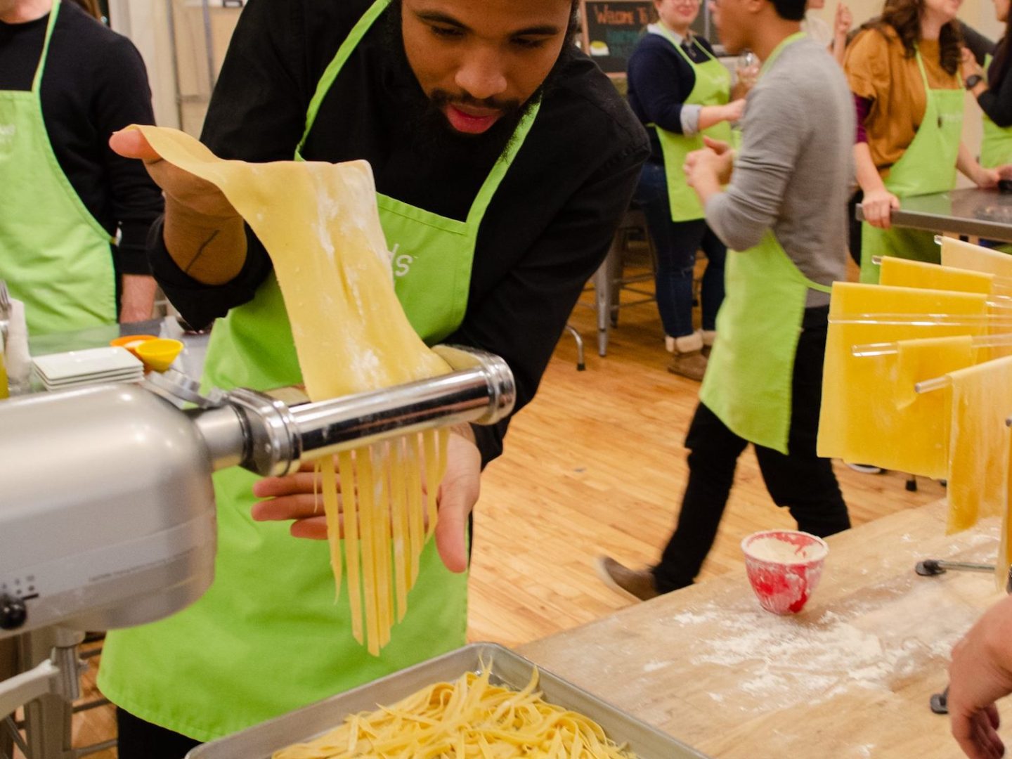 a man feeding handmade pasta into a cutting machine