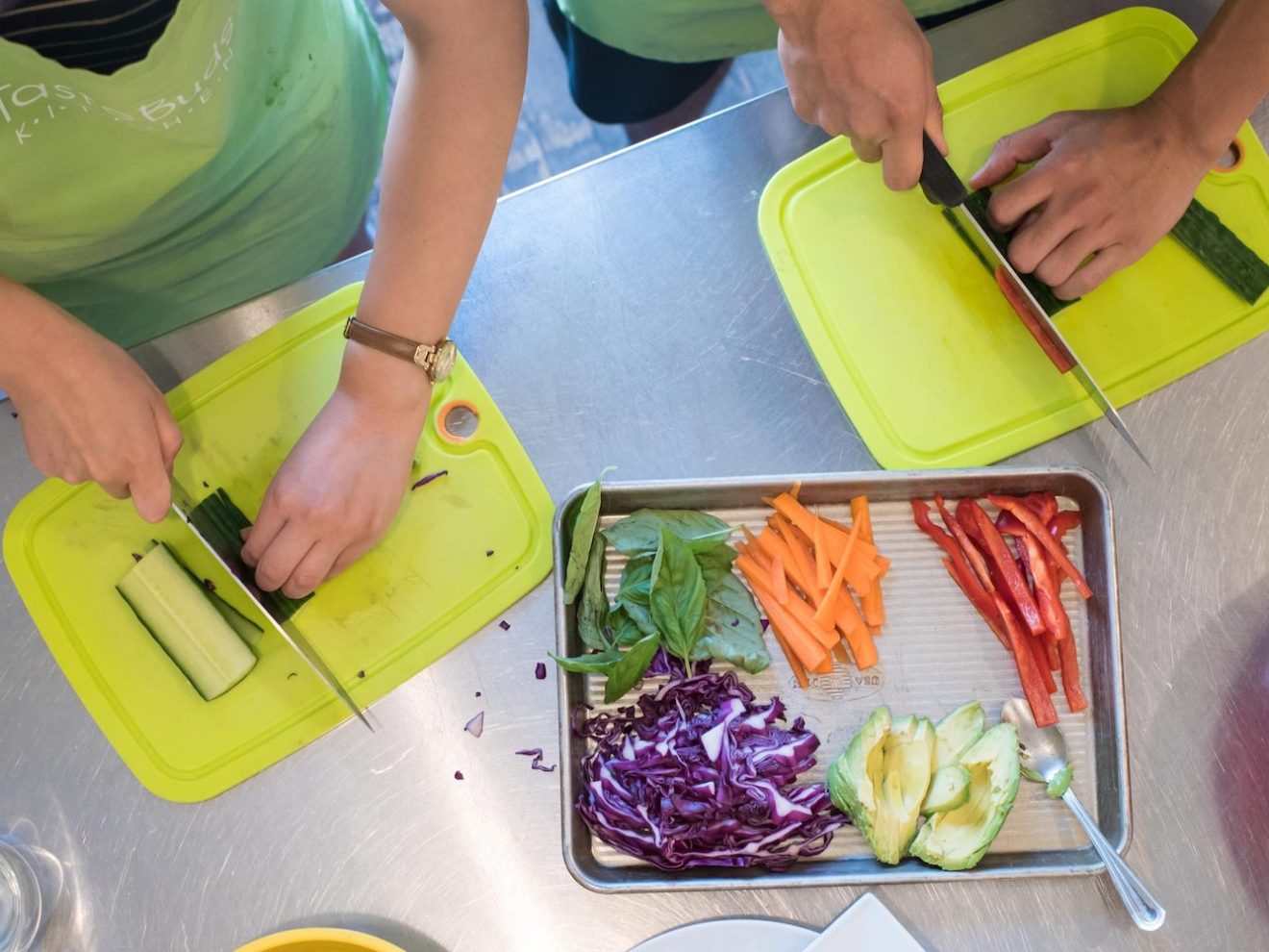 two people cutting vegetables on a cutting board