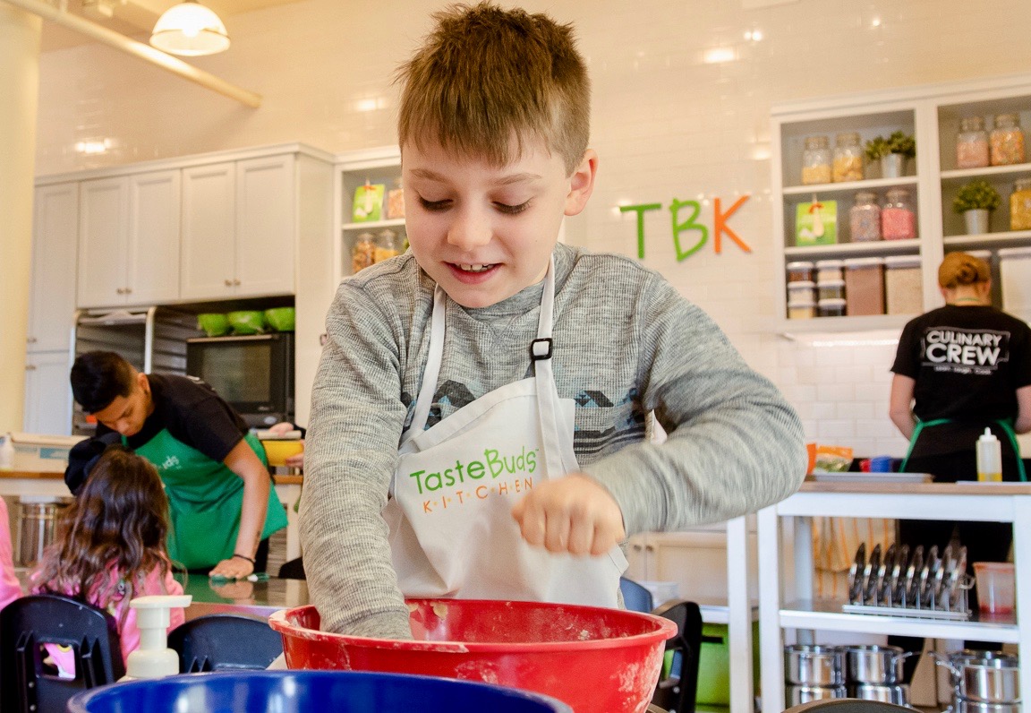 a boy with his hands in a mixing bowl