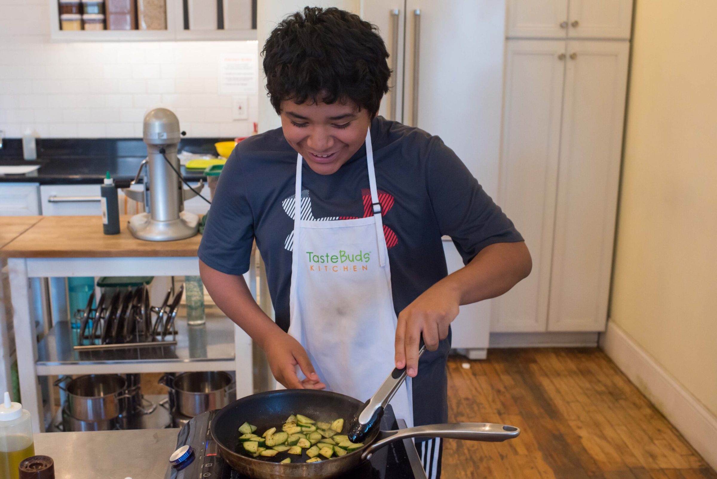 a boy is preparing zucchini in a pan