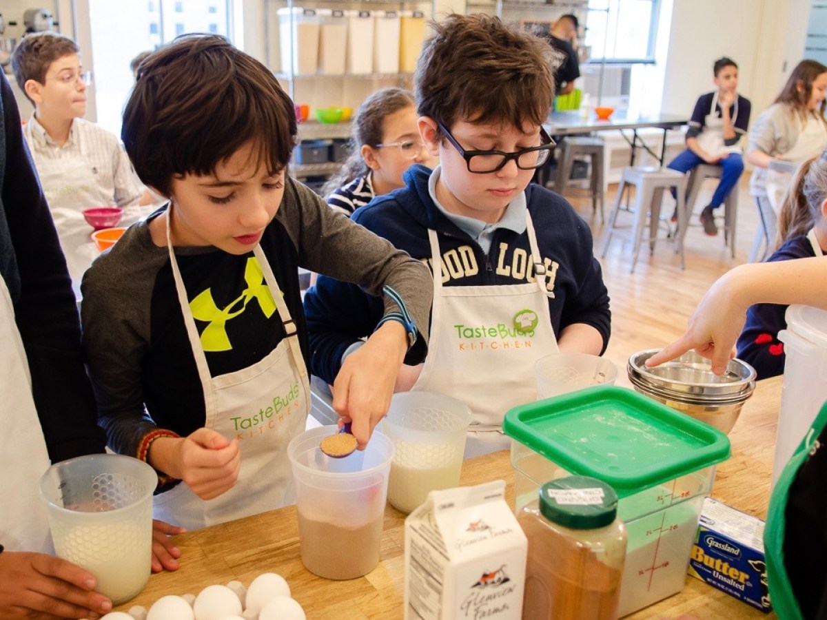 two kids measuring ingredients at the kitchen table
