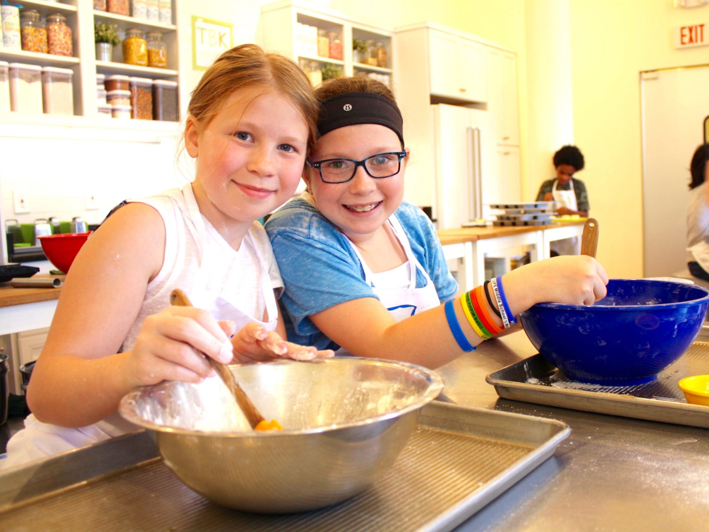 two girls stirring using mixing bowls