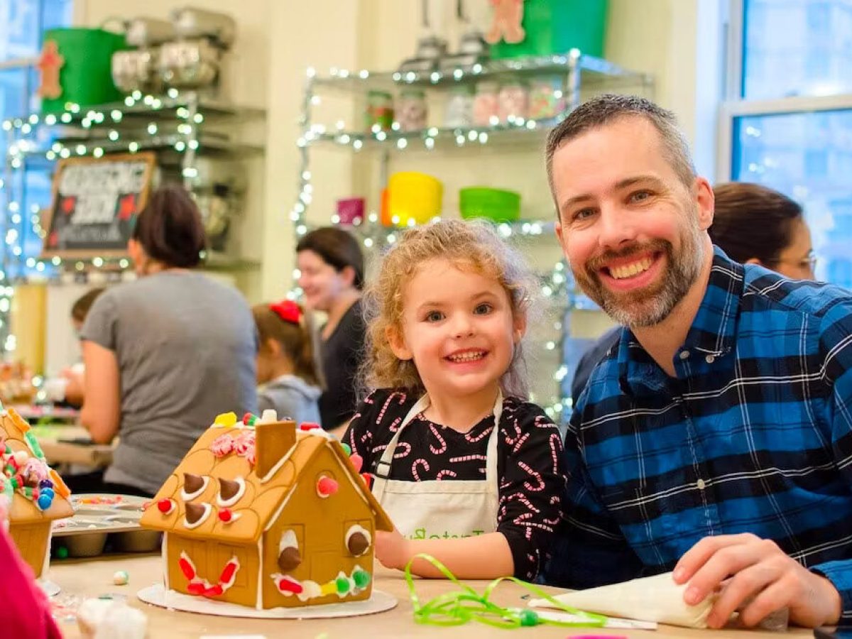 a dad and daughter making a gingerbread house