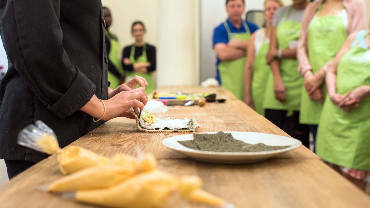 a group of people sitting on a cutting board with a cake